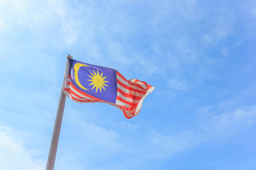 Malaysian national flag on a pole against blue sky