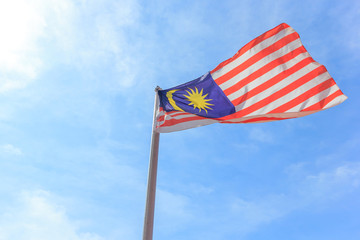 Malaysian national flag on a pole against blue sky