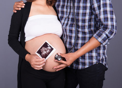 close up pregnant and husband with stethoscope and ultrasound im