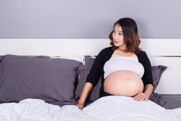 pregnant woman lying on bed in the bedroom