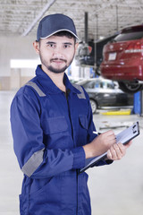 Arabic mechanic holds clipboard in workshop