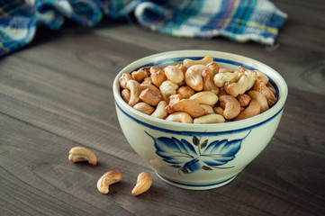 Roasted cashew nuts in a bowl on natural background wooden table