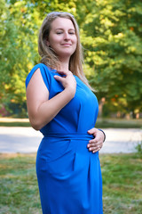 beautiful woman in blue gown posing in city park