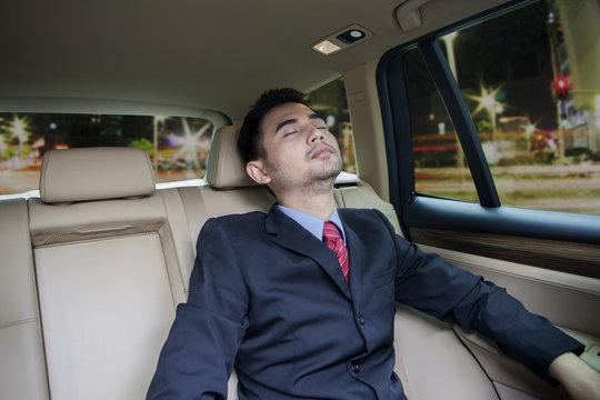Male worker sleeping inside a car