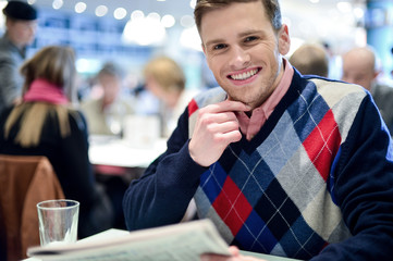 Happy young man in cafe posing to camera.