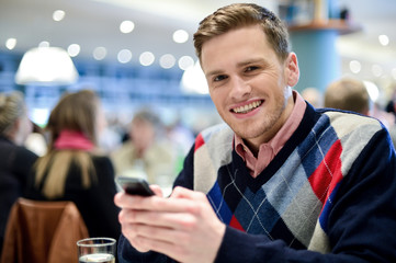 Man at cafe, texting with his friend.