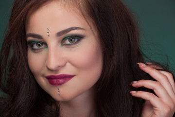 Close-up portrait, girl with green eye shadows, make-up, facial stones crystals