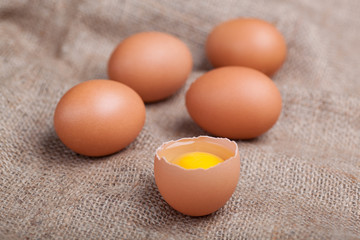 Fresh eggs on sacking, broken eggshell, yolk