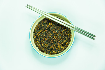 Brown rice in bowl with chopsticks on white paper background