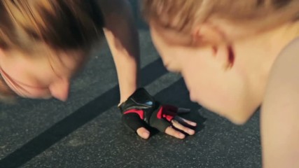 Two young women doing push-ups and clapping hands