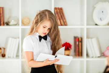 little schoolgirl in school uniform reading the textbook