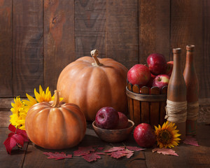 Autumn still life - pumpkins, autumn leaves and apples against the background of old wooden wall.