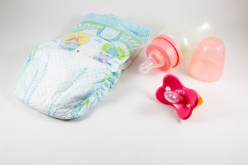 Bottles, pacifiers, and baby diaper on a white background