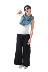 Fototapeta premium Expressive short hair brunette with sunglasses showing heavy metal hand sign. Full body length portrait isolated over white studio background.