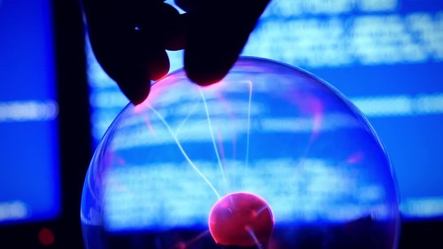 Plasma Ball - a transparent sphere filled with rarefied inert gas. Slowmotion of Hand touch the plasma ball against a blue background broken computer