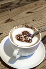 Cup of delicious coffee with foam milk and heart made of cinnamo