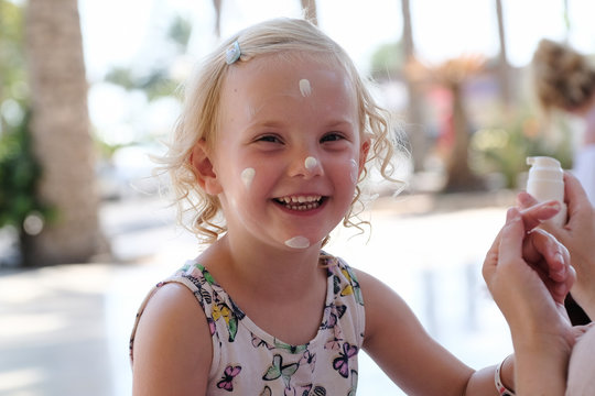 kleines blondes M&auml;dchen beim auftragen von sonnencreme
