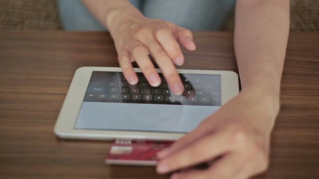 Woman's hands holding a credit card and using tablet for online shopping. Closeup shot