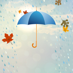Blue opened umbrella with rain and falling leaves