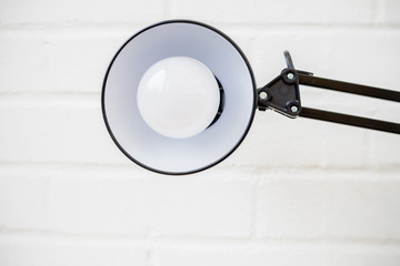 Anglepoise lamp. Bulb and light in mid frame with white brick ba