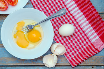 Broken raw eggs on a white plate.