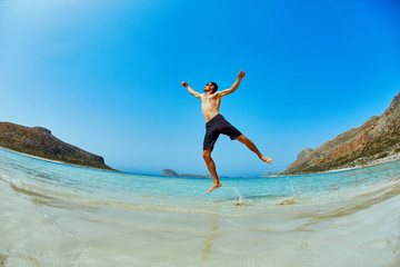 man standing in the sea on the beach. Smiling man looking at camera and He raises both hands up as if playing the ball