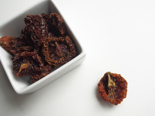 Dried tomatoes in container on white backgroundo
