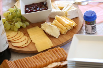 cheese platter with cherry preserves, grapes and various cheeses