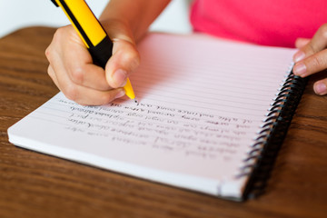 Child writing by hand on notepad