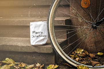 white bag for gifts with the words "Merry Christmas" on the porch next to a bicycle parked near © Alex Tor