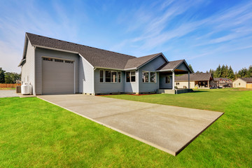 Fototapeta premium Backyard view of blue house with garage and green grass.