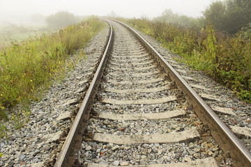 Fototapeta na wymiar Empty railroad track going into a fog. Perspective view.