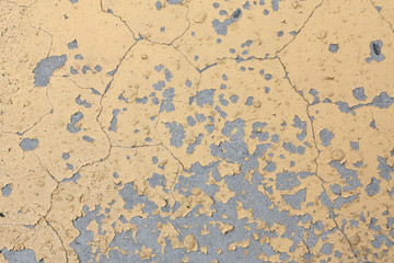 Background of light yellow cracked paint on an old concrete wall