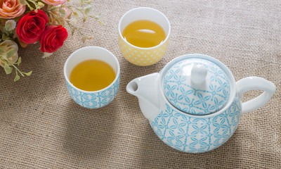 hot green tea and tea pot on sackcloth.