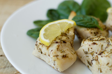 Chopped chicken fillet baked with thyme and served with fresh lemon slice and small spinach leaves