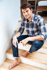 Portrait of a young handsome man sitting on the staircase