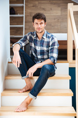 Portrait of a young handsome man sitting on the staircase