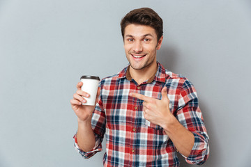 Young handsome smiling man pointing finger at takeaway coffee cup