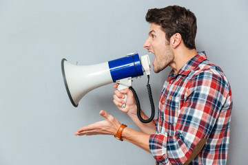 Side view portrait of a casual man yelling into megaphone
