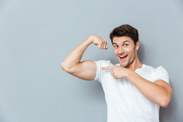 Smiling man pointing on his biceps - obrazy, fototapety, plakaty