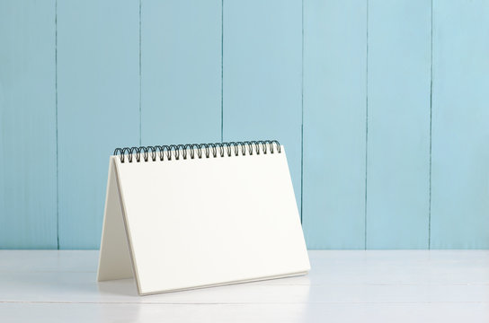Blank desk calendar on white and blue wooden background