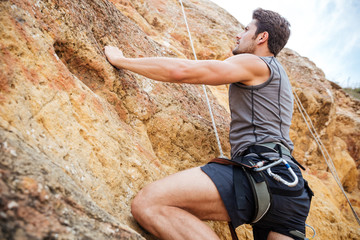 Young man climbing a steep wall in mountain