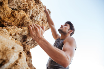 Young man climbing natural rocky wall
