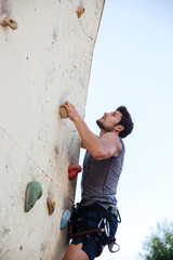 Young man doing exercise in mountain climbing on practice wall