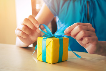 woman making gift box decorating with ribbon
