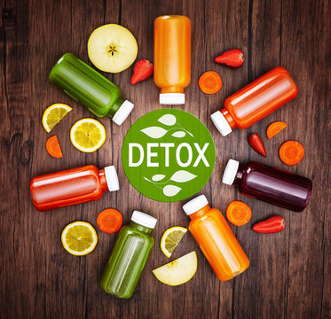 Bottles with delicious detox drinks and text detox on wooden background. Detox diet concept.