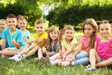 Happy kids sitting on grass in park