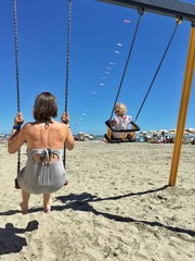 mamma e bimba sull'altalena in spiaggia
