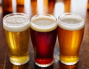 three different types of beer in glass mugs