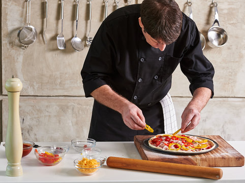 Restaurant hotel private chef preparing pizza adding toppings